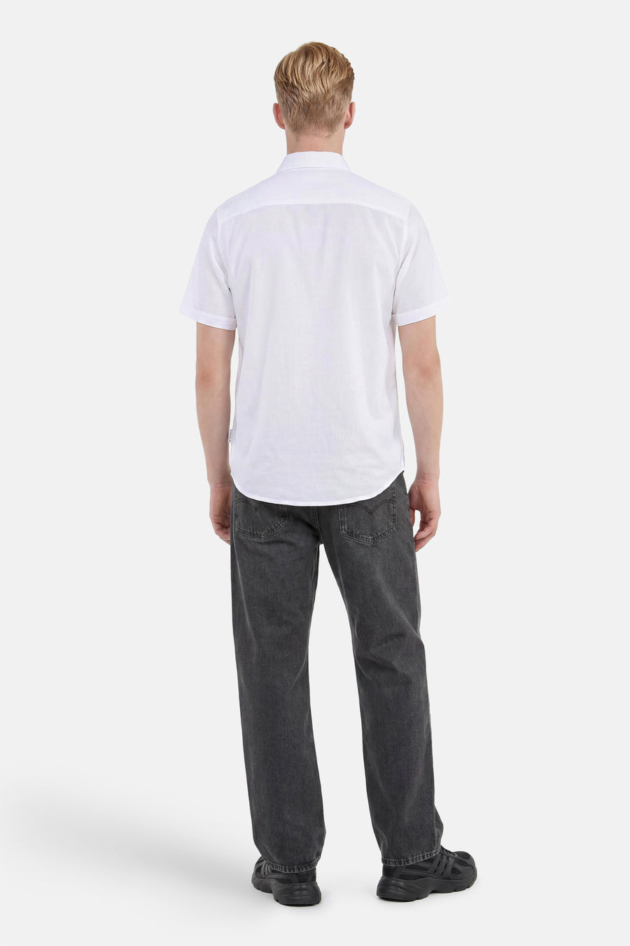 Chemise blanche à manches courtes de TOM TAILOR, portée par un homme en jean gris foncé et baskets noires, vue de dos.