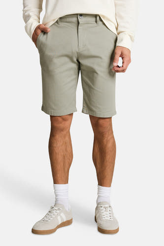 Shorts verts TOM TAILOR en tissu uni, avec une poche passepoilée et des passants de ceinture, vus de dos sur un homme portant une chemise gaufrée de couleur crème et des baskets blanches.
