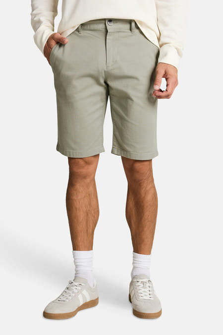 Groene chino shorts van TOM TAILOR, gedragen met een crème wafelpatroon shirt en lichte sneakers.