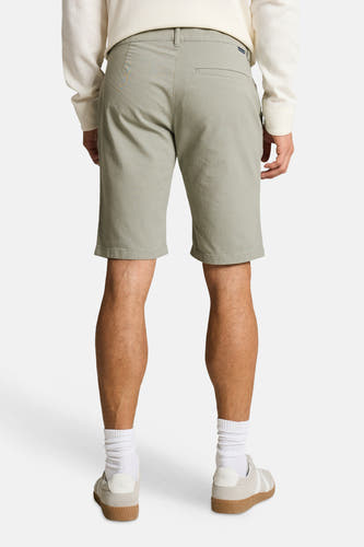 Groene shorts van TOM TAILOR in effen stof, met een paspelzak en riemlussen, van achteren gezien op een man met een crèmekleurig wafelshirt en witte sneakers.