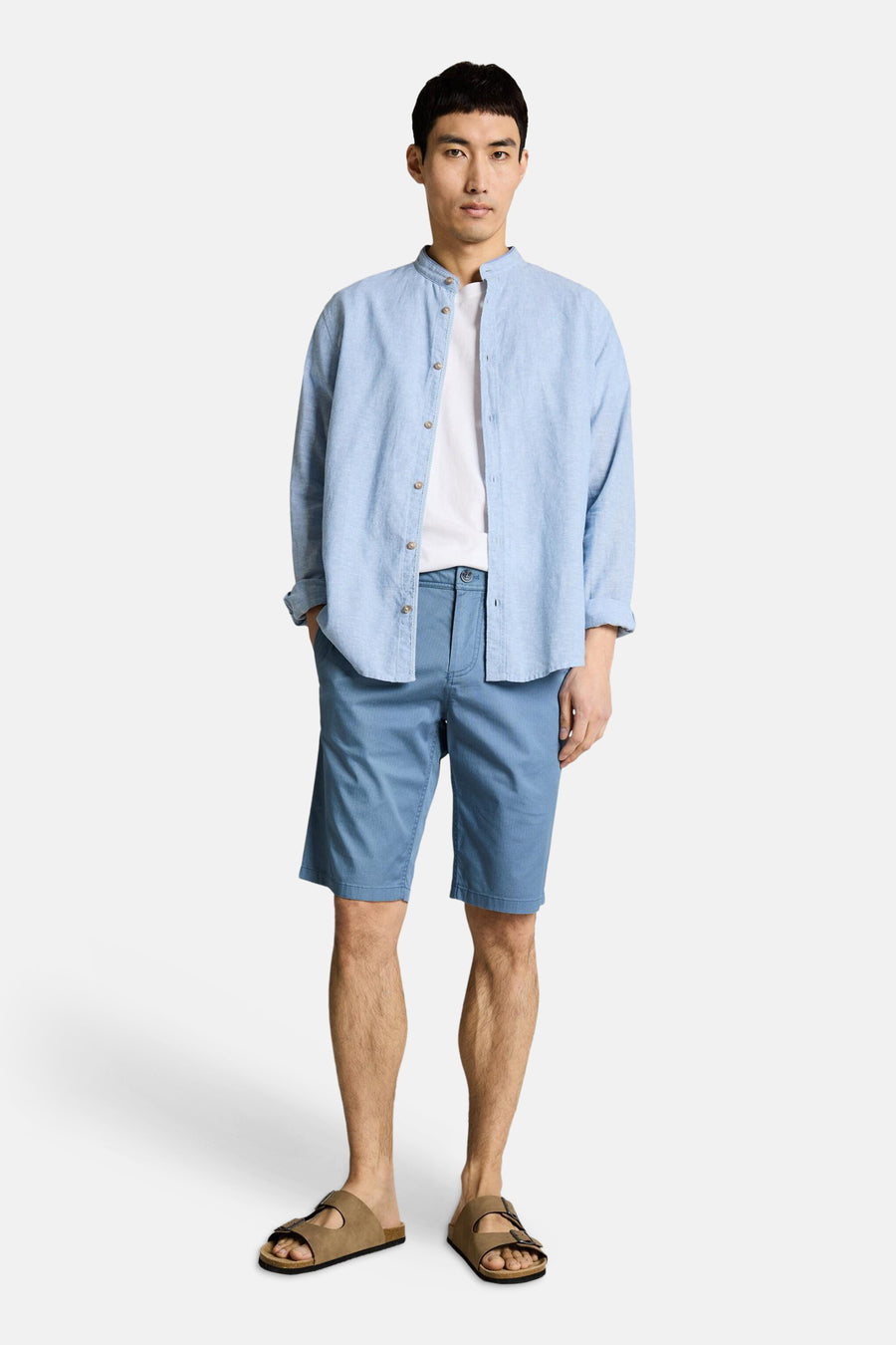 Blauwe bermuda van TOM TAILOR, gedragen met een wit T-shirt en een lichtblauw linnen overhemd, gecombineerd met bruine sandalen.