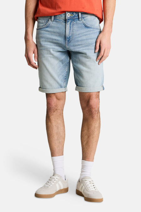 Jeansshort van lichtblauwe denim van TOM TAILOR, met opgerolde pijpen, gecombineerd met witte sokken en sneakers.