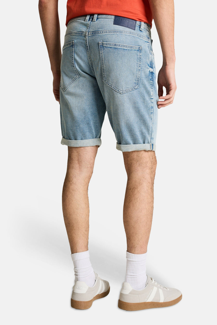 Jeansshort van lichtblauw denim van TOM TAILOR, met opgerolde pijpen en witte sokken met sportschoenen.
