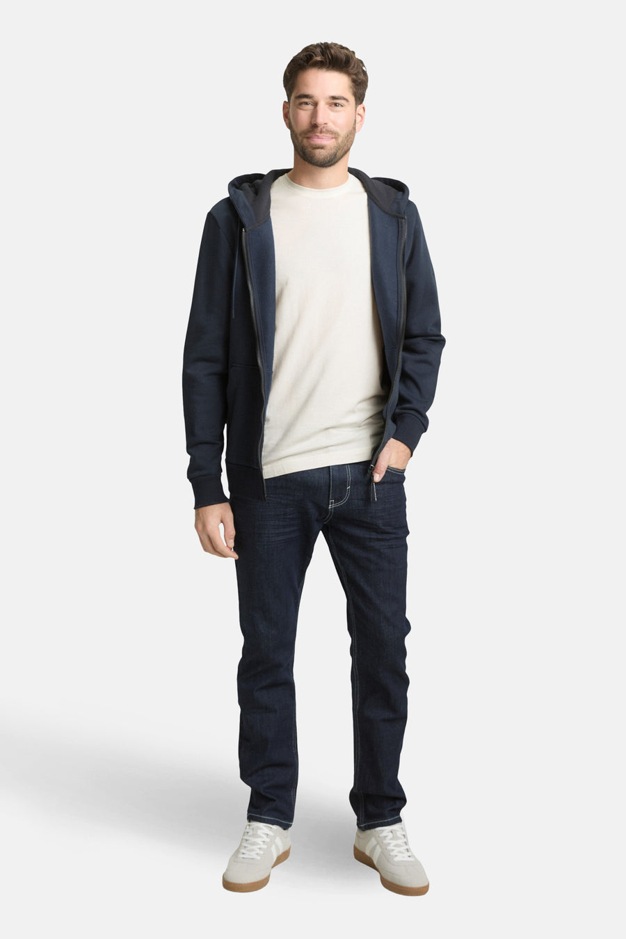 Wit T-shirt met korte mouwen van TOM TAILOR, gedragen onder een marineblauw vest met rits en donkere jeans.
