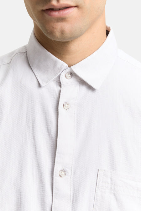 Wit overhemd met knopen en borstzak.
