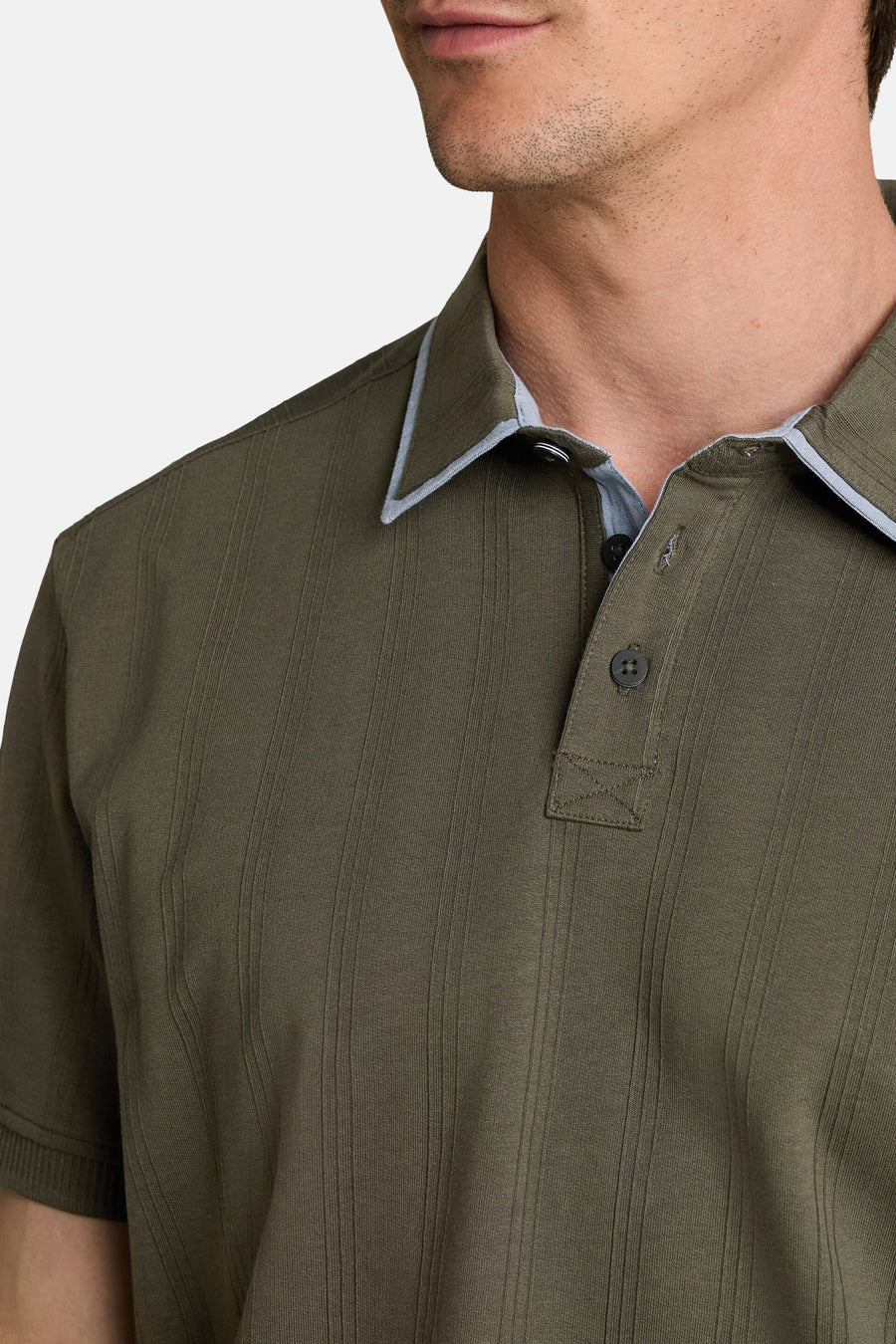 Groene polo met ribstructuur van TOM TAILOR, lichtblauwe kraagaccenten en donkere knopen, close-up van bovenkant