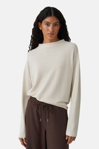 Beige T-shirt met lange mouwen van OPUS, met een subtiele wafeltextuur en gecombineerd met een bruine broek met trekkoord.
