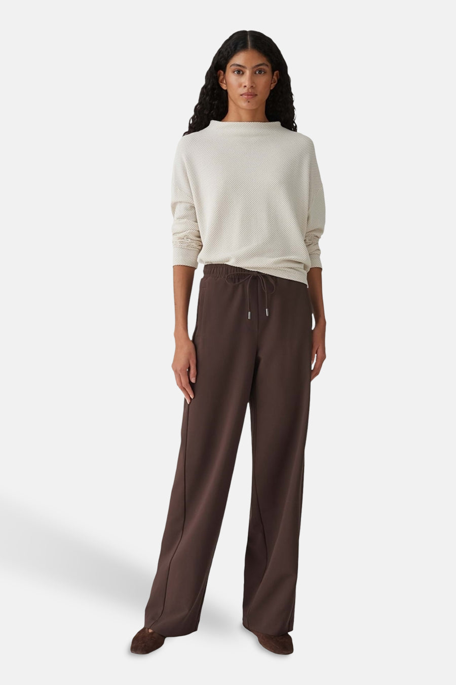 Beige T-shirt met lange mouwen van OPUS, met een subtiele textuur en gedragen met bruine, wijde broek.
