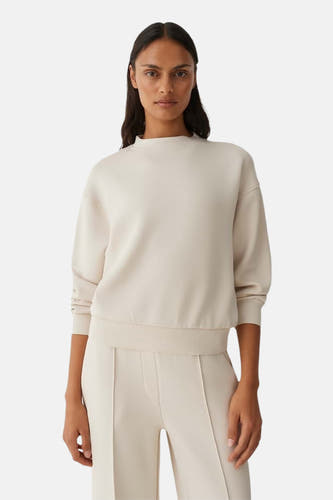 Pull beige à col rond d'OPUS, vu de dos, avec pantalon assorti et baskets blanches.