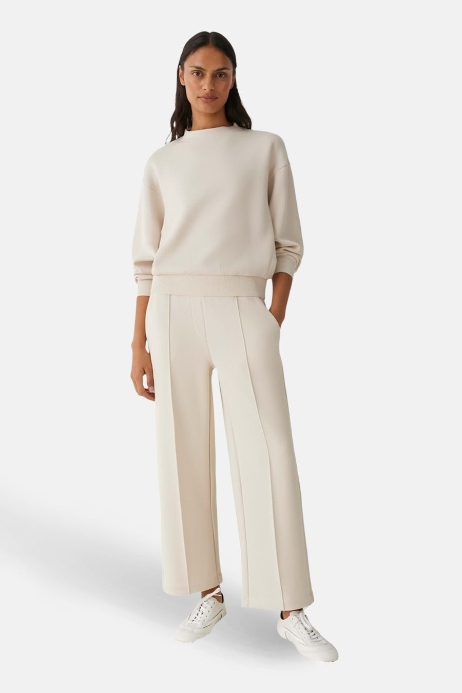 Beige trui met ronde hals van OPUS, gedragen met crèmekleurige broek en witte sneakers.
