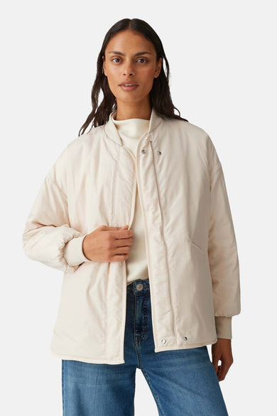 Manteau beige OPUS, à motif à carreaux et manches longues, porté avec un jean ample et des mocassins.