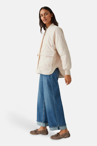 Beige jas van OPUS, met diamantstiksels, lange mouwen en opgestikte zakken, gedragen met wijde jeans en mocassins.