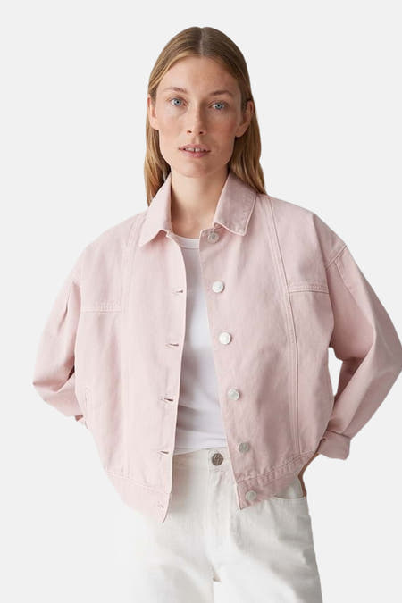 Roze jeansjas van OPUS, met lange mouwen en knoopsluiting, gecombineerd met een wit t-shirt en een witte broek.
