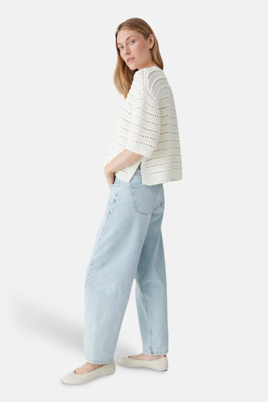 Ecru trui met ronde hals van OPUS, met open gebreide details, gecombineerd met lichtblauwe jeans en platte schoenen.