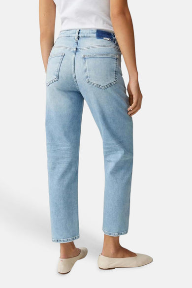 Lichtblauwe denim Mom Jeans van OPUS, van achteren gezien, met hoge taille, rechte pijpen en enkellengte, gedragen met witte top en beige ballerina's.