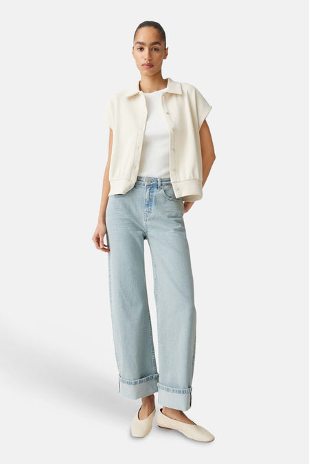 Lichtblauwe denim wide jeans van OPUS, met omgeslagen pijpen, gestyled met een wit shirt en crème schoenen.