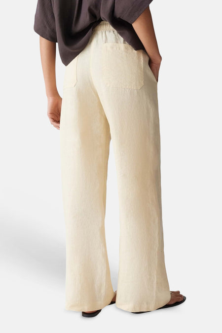 Lichtgele dames seizoensbroek van OPUS met elastische taille, wijde pijpen en achterzakken, vanuit de rug gezien.
