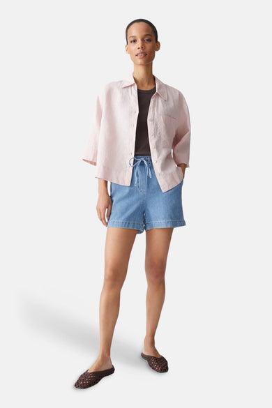 Lichtblauwe denim korte broek van OPUS, met elastische taille en trekkoord, gedragen met roze overhemd en bruine vlechtjeslippers.