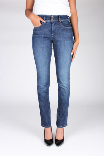 Une femme portant une chemise blanche, des jeans bleus et des talons noirs.