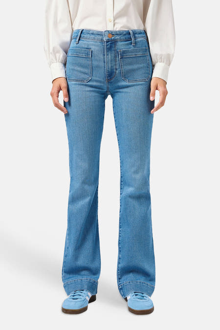 Lichtblauwe denim flared jeans van Wrangler met opgestikte zakken, gedragen met een wit overhemd en blauwe sneakers.