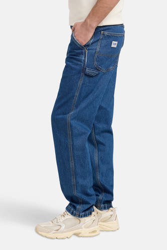 Jean droit en denim bleu, de Lee, avec poche de pantalon et sneakers claires.