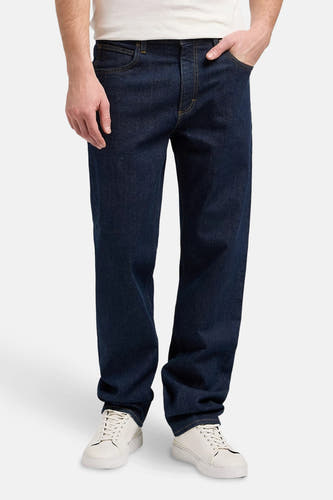 Jean tapered bleu marine de Lee, avec surpiqûres dorées et baskets blanches.