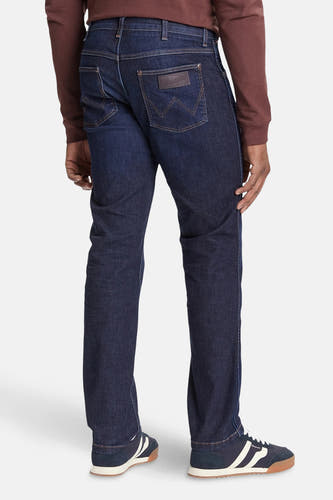Jeans straight van donkerblauw denim van Wrangler, achterkant getoond, gecombineerd met een bruin shirt en sneakers.
