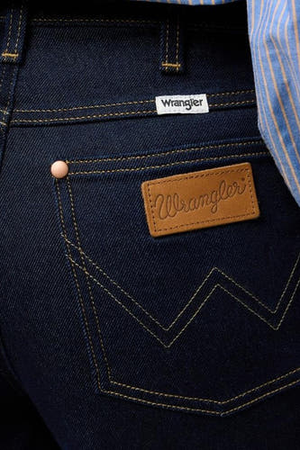 Jean large de Wrangler en denim bleu foncé, avec des boutons caractéristiques sur la poche arrière et un patch logo.