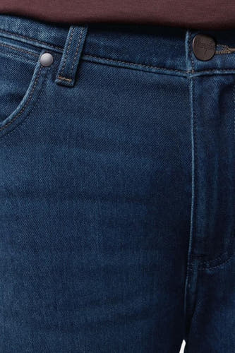 Jean tapered bleu marine en denim de Wrangler, avec ceinture, poche et passant de ceinture.