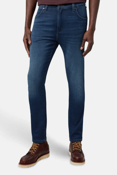Donkerblauwe denim tapered jeans van Wrangler, gedragen met bruine leren laarzen met veters.