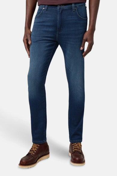 Donkerblauwe denim tapered jeans van Wrangler, gedragen met bruine leren laarzen met veters.