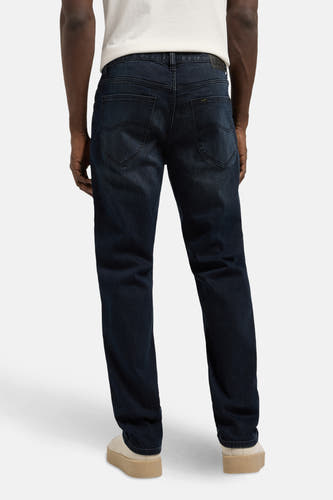 Jean droit en denim bleu-noir de Lee, vu de derrière, avec des chaussures beige.