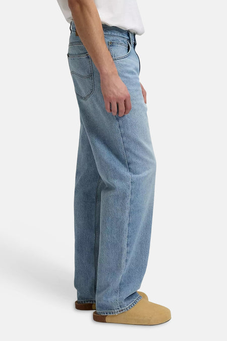 Lichtblauwe wide-leg jeans van Lee®, gedragen met een wit T-shirt en beige klompen, zijaanzicht.