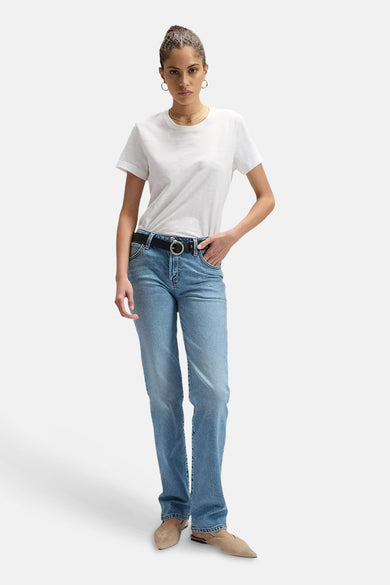 Lichtblauwe straight jeans van Lee® met een zwarte riem, gecombineerd met een wit t-shirt en beige schoenen.
