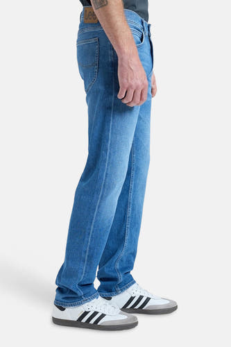 Blauwe rechte jeans van Lee, in een middentint, met witte sneakers met zwarte strepen.