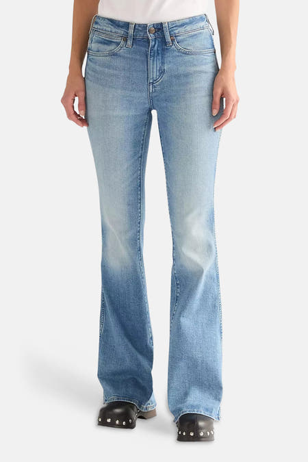 Flared jeans van mid-blauwe denim van Wrangler®, gedragen met zwarte klompen met studs.