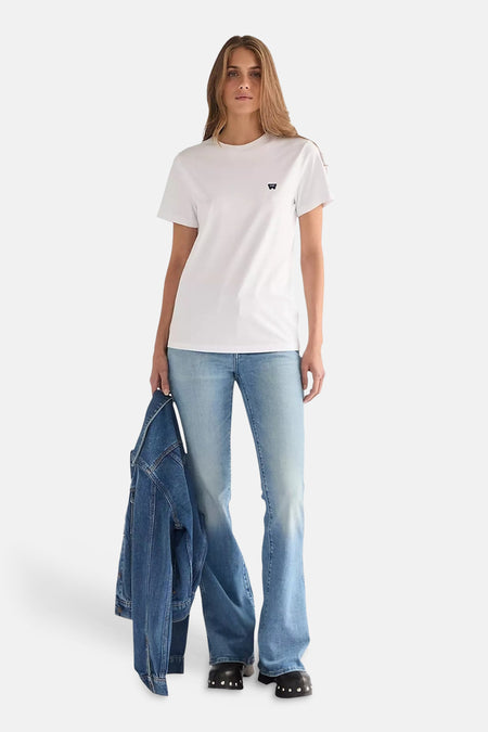 Mid blauwe flared jeans van Wrangler®, gedragen door een vrouw met een wit T-shirt en spijkerjas.