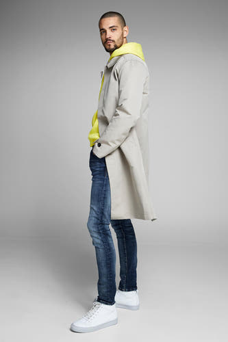 Slim fit jeans van JACK & JONES JEANS INTELLIGENCE, gedragen met gele hoodie en beige trenchcoat.