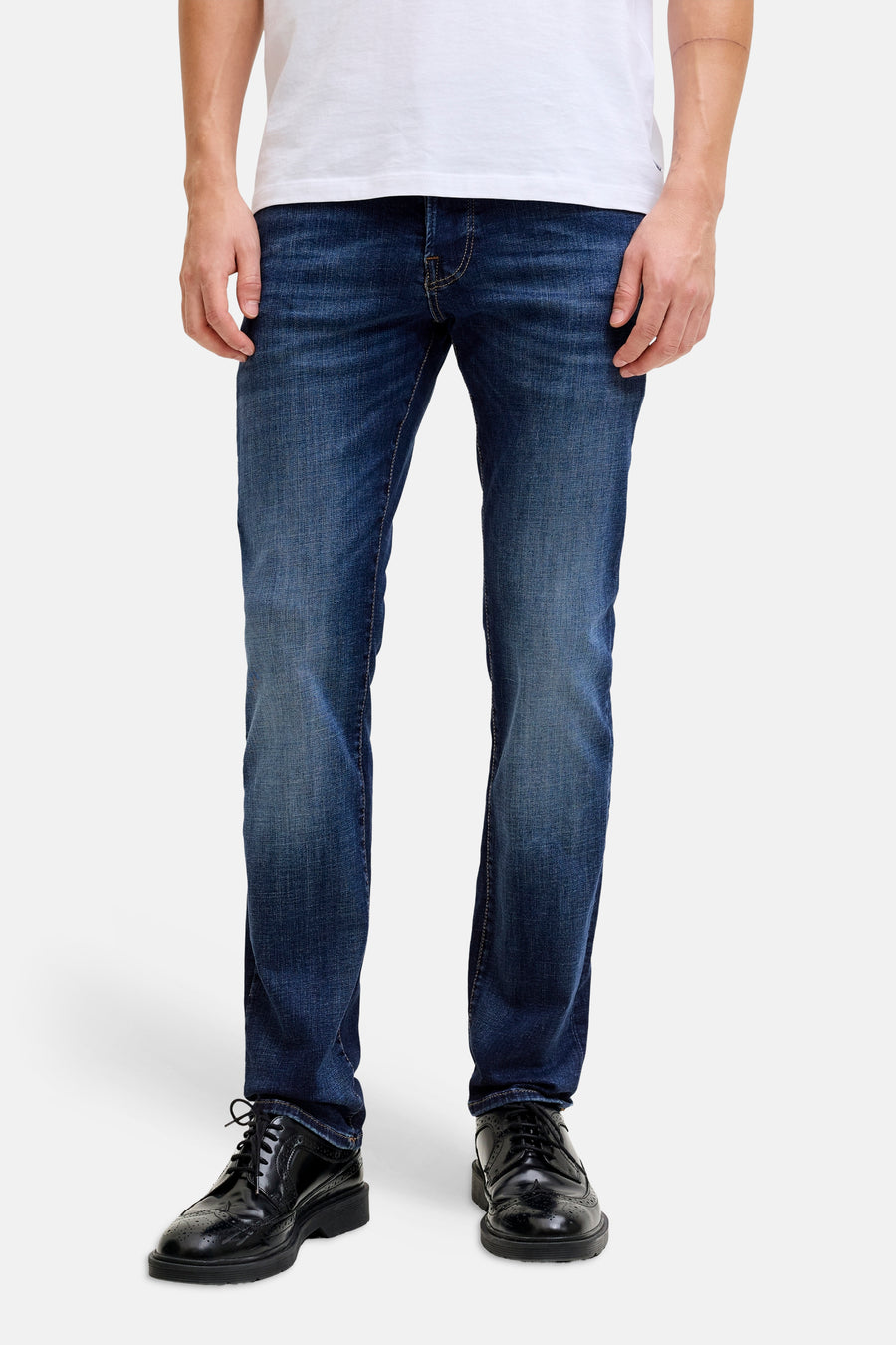 Slim fit jeans in mid blue denim van JACK & JONES JEANS INTELLIGENCE, gedragen met een wit T-shirt en zwarte schoenen.

