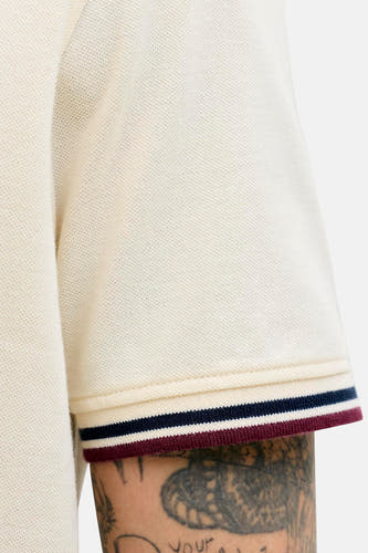 Polo écru de PREMIUM by JACK & JONES, avec des bords rayés et une texture piqué, gros plan sur la manche.