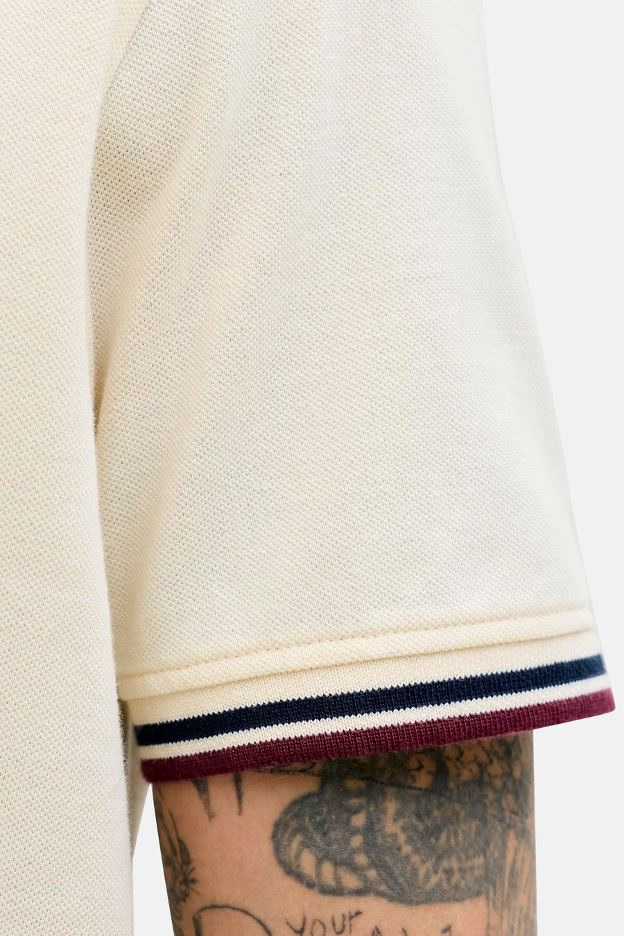 Polo écru de PREMIUM by JACK & JONES, avec des bords rayés et une texture piqué, gros plan sur la manche.