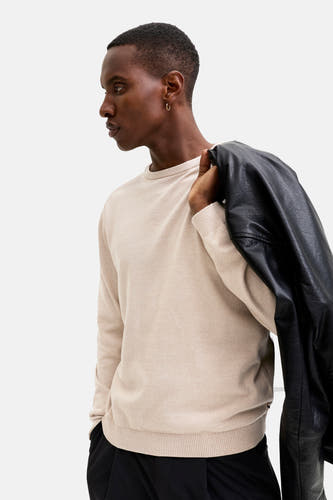 Gilet beige avec col rond de CORE BY JACK & JONES, avec un manteau en cuir drapé sur l'épaule.