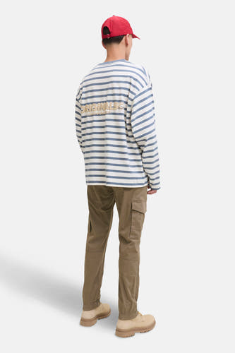Bruine cargobroek van JACK & JONES JEANS INTELLIGENCE, met zakken en gedragen met een gestreept shirt en rode pet.
