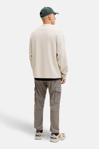 Pantalon de travail brun de JACK & JONES JEANS INTELLIGENCE, avec des poches sur les côtés et porté avec un pull beige et des baskets.