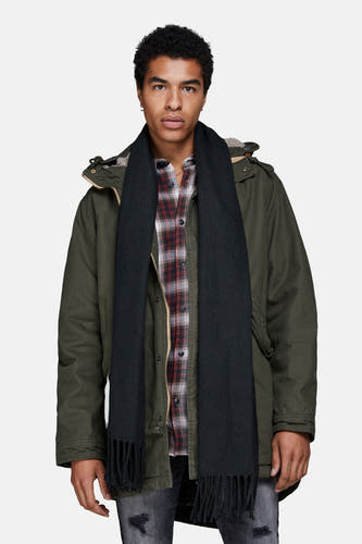 Zwarte wintersjaal van ACCESSORIES BY JACK & JONES, met franjes, gedragen met een geruit overhemd en een parka.
