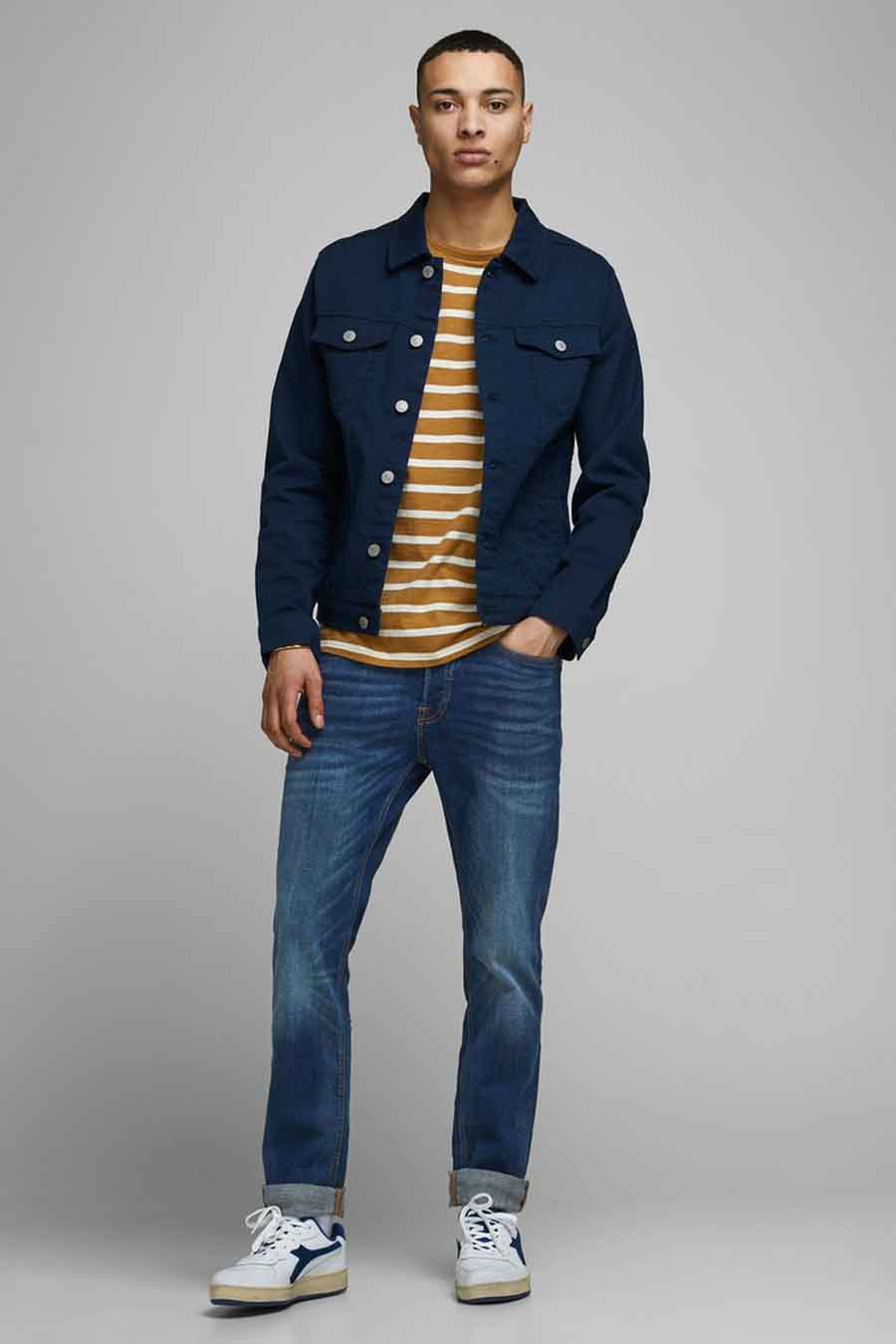 Man met blauwe spijkerjas, gestreept shirt, jeans en sneakers.
