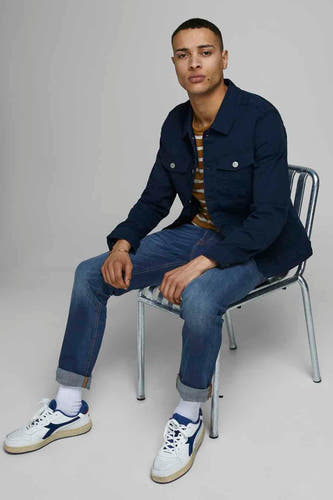 Slim fit jeans van JACK & JONES JEANS INTELLIGENCE, in mid blue denim, gedragen met een marineblauw overhemd en sneakers.
