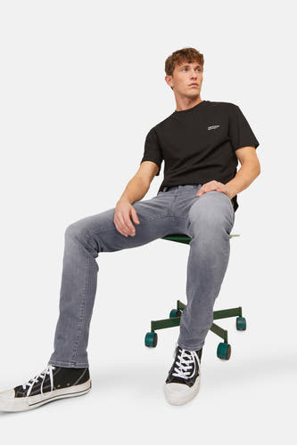 Jean slim de denim gris clair de JACK & JONES JEANS INTELLIGENCE, porté avec un T-shirt noir et des baskets basses.