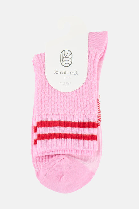 Chaussettes roses BIRDLAND avec une texture tricotée, deux rayures rouges et une étiquette blanche.