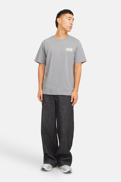 Grijs T-shirt met korte mouwen van CORE by JACK & JONES, met klein logo op de borst, gecombineerd met wijde jeans en sneakers.
